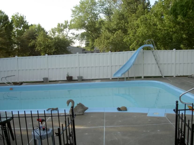 Swimming pool with a slide and surrounding greenery.