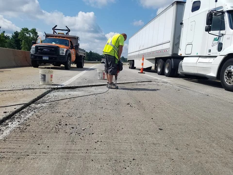 Construction worker repairing highway pavement with machinery